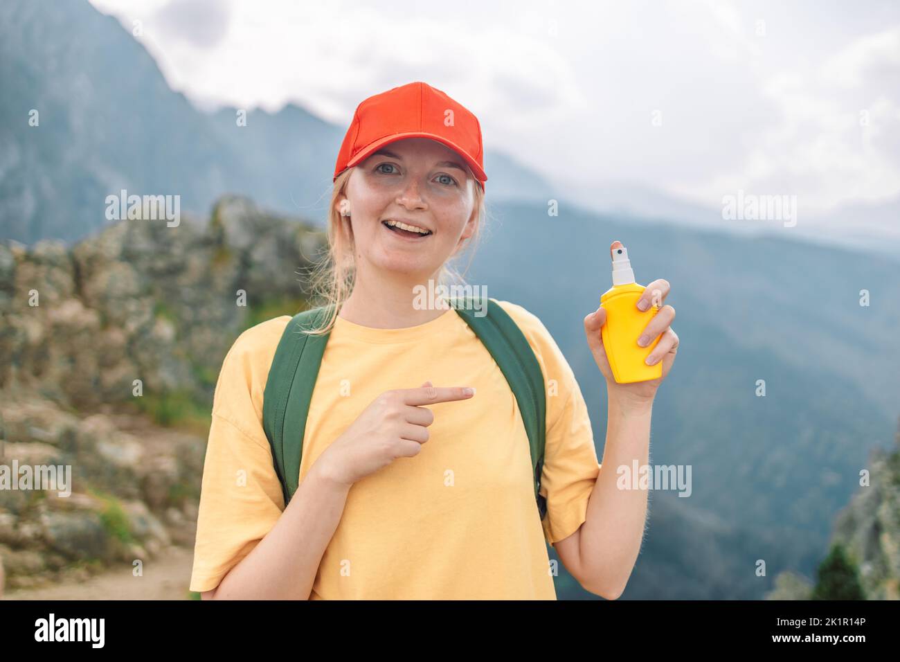 Donna che applica repellente insetto contro zanzara e zecca sulla sua mano durante l'escursione in montagna natura. Protezione della pelle contro il morso di insetto Foto Stock