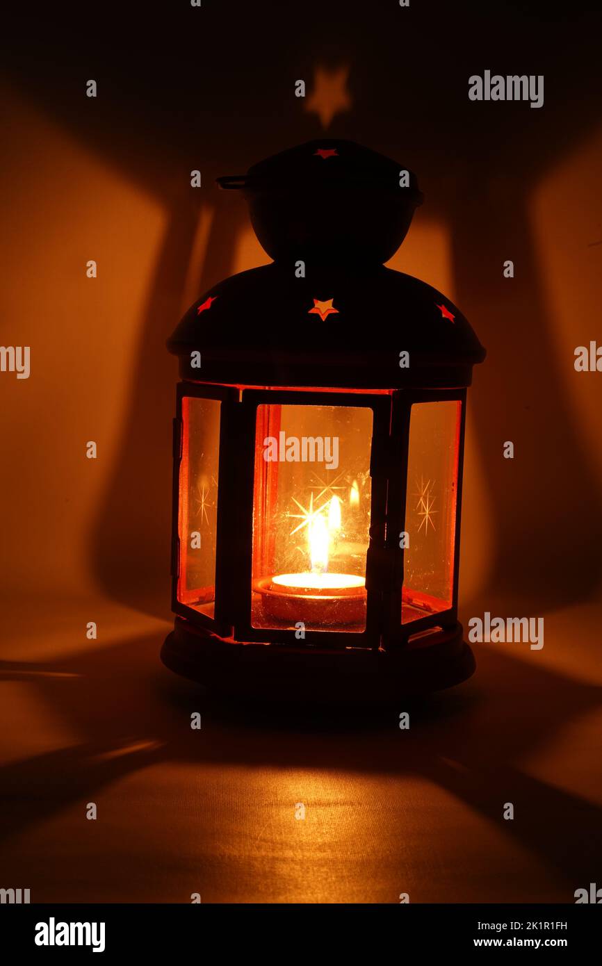 Incenso bruciatore censitore con fumo e sfondo bianco. Ornamentale lanterna araba con candela incandescente in mano. Foto Stock