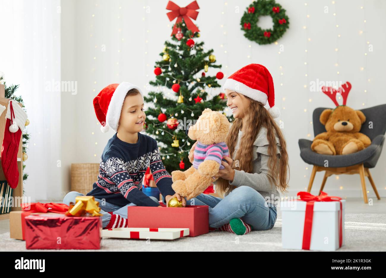 I bambini sorridenti aprono i regali insieme nelle feste di Capodanno Foto Stock