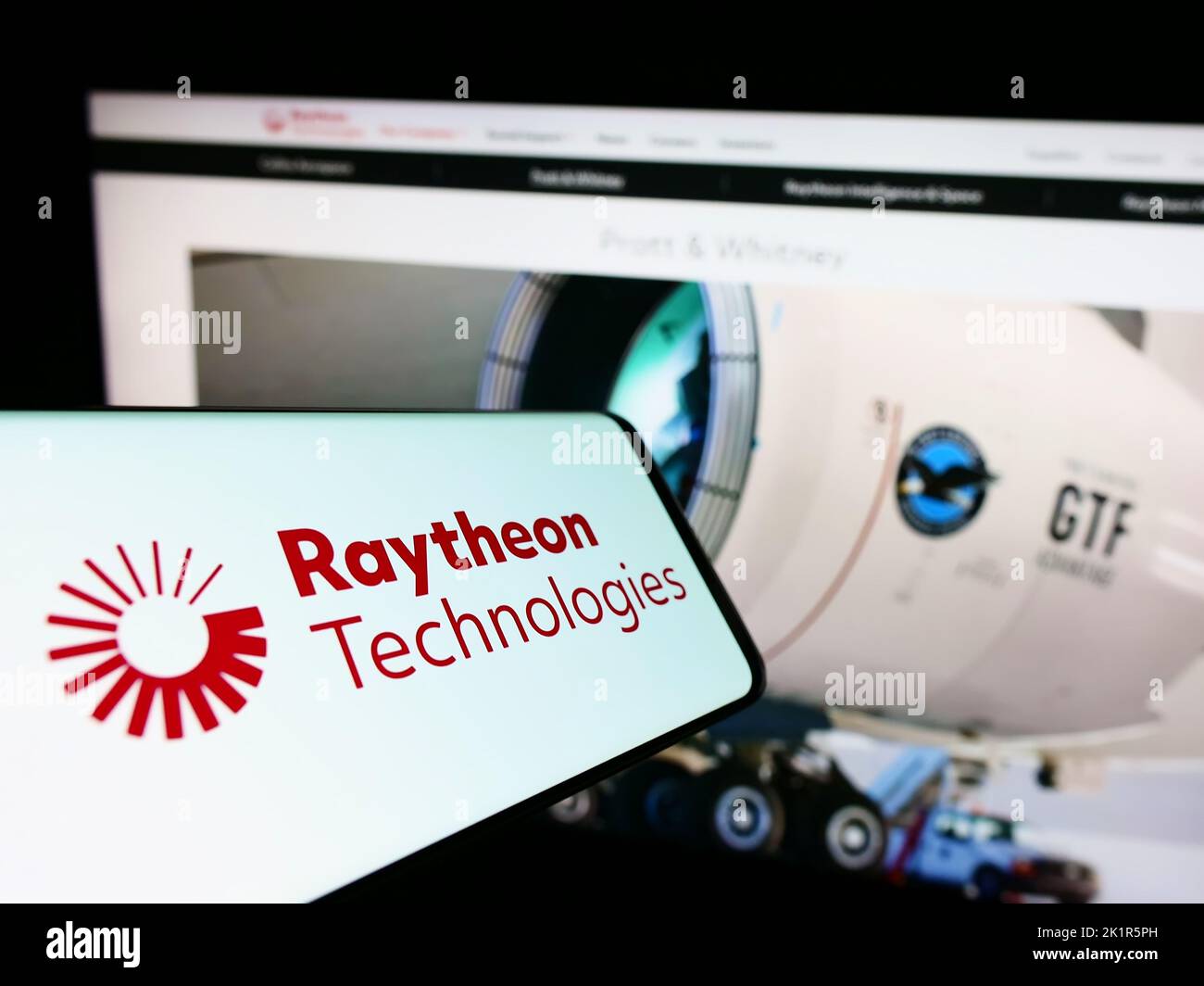 Cellulare con il logo della società statunitense Raytheon Technologies Corporation sullo schermo di fronte al sito Web. Messa a fuoco al centro a destra del display del telefono. Foto Stock