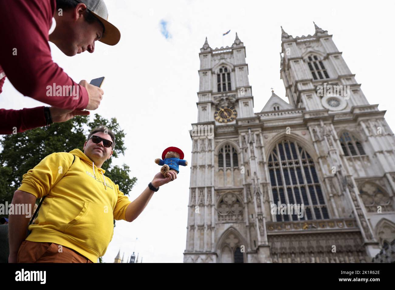 Un uomo si pone per una foto con un giocattolo Paddington Bear fuori Westminster Abbey, a seguito dei funerali della regina Elisabetta britannica, a Londra, Gran Bretagna 20 settembre 2022. REUTERS/Tom Nicholson Foto Stock
