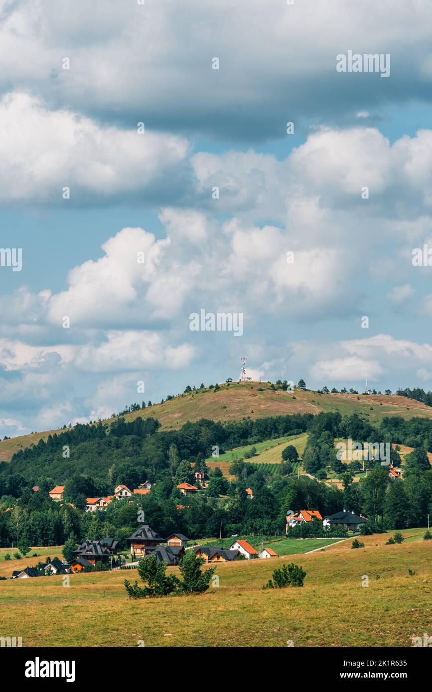 Bellissimo paesaggio pittoresco della regione di Zlatibor con case in stile architettonico distintivo sparse sulle verdi colline nelle soleggiate giornate estive Foto Stock