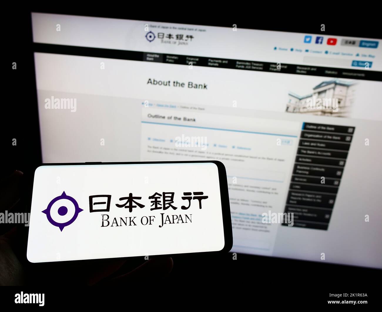 Persona che tiene uno smartphone con il logo dell'istituto finanziario Bank of Japan (BOJ) sullo schermo di fronte al sito Web. Messa a fuoco sul display del telefono. Foto Stock