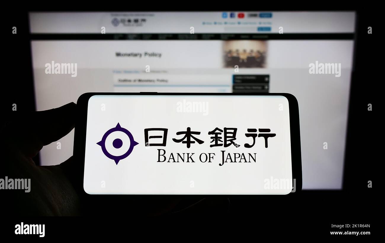 Persona che detiene un telefono cellulare con il logo dell'istituto finanziario Bank of Japan (BOJ) sullo schermo di fronte alla pagina web. Messa a fuoco sul display del telefono. Foto Stock