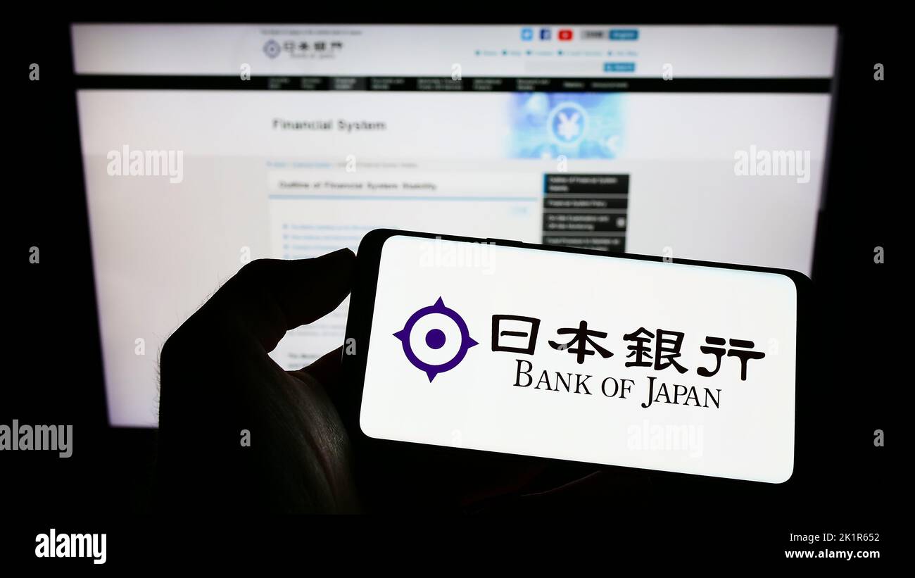Persona che tiene il cellulare con il logo dell'istituto finanziario Banca del Giappone (BOJ) sullo schermo davanti alla pagina web. Messa a fuoco sul display del telefono. Foto Stock