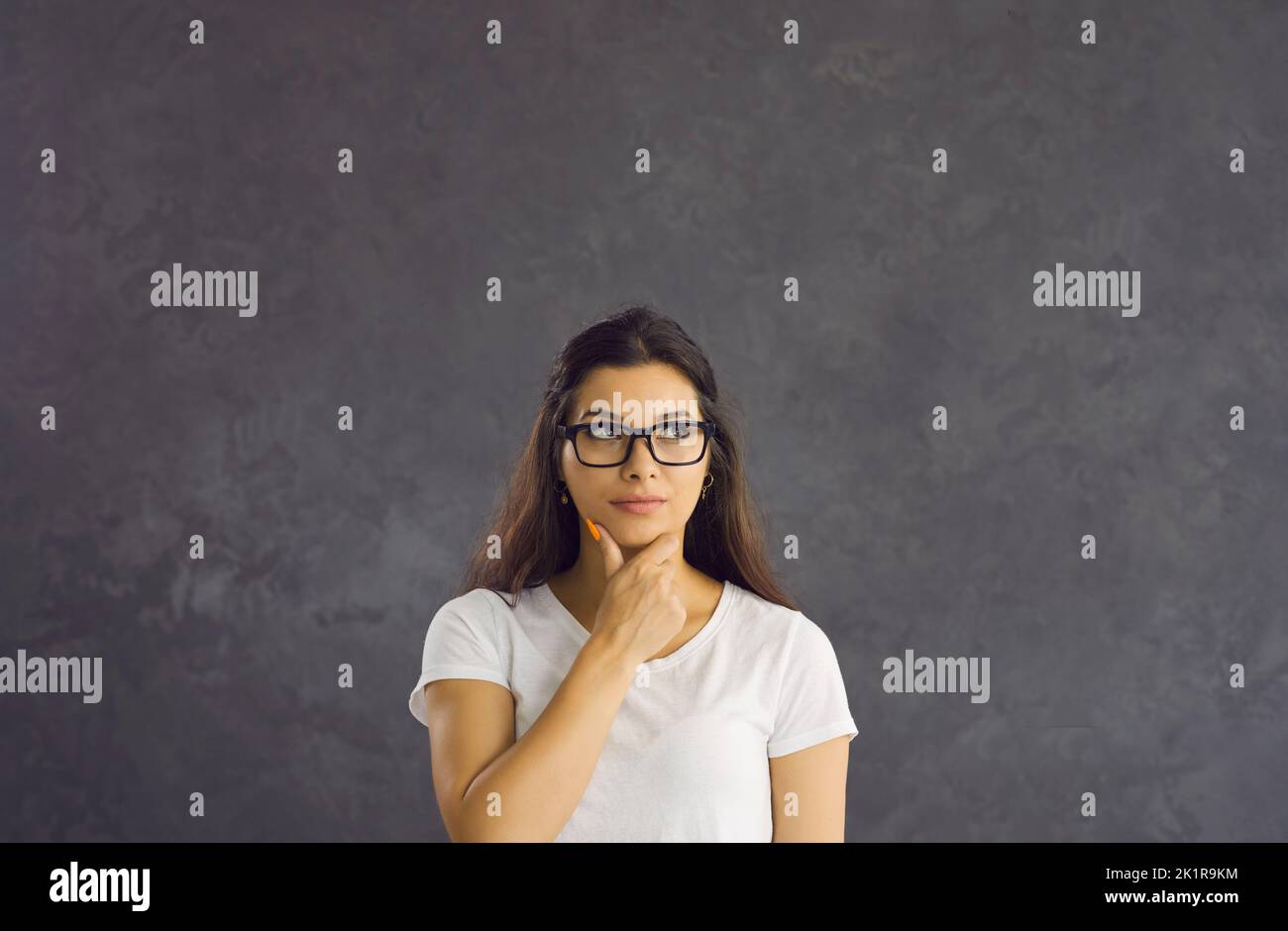 Ritratto di una donna imbarazzata che pensa a qualcosa di interessante o che pensa a qualcosa. Foto Stock