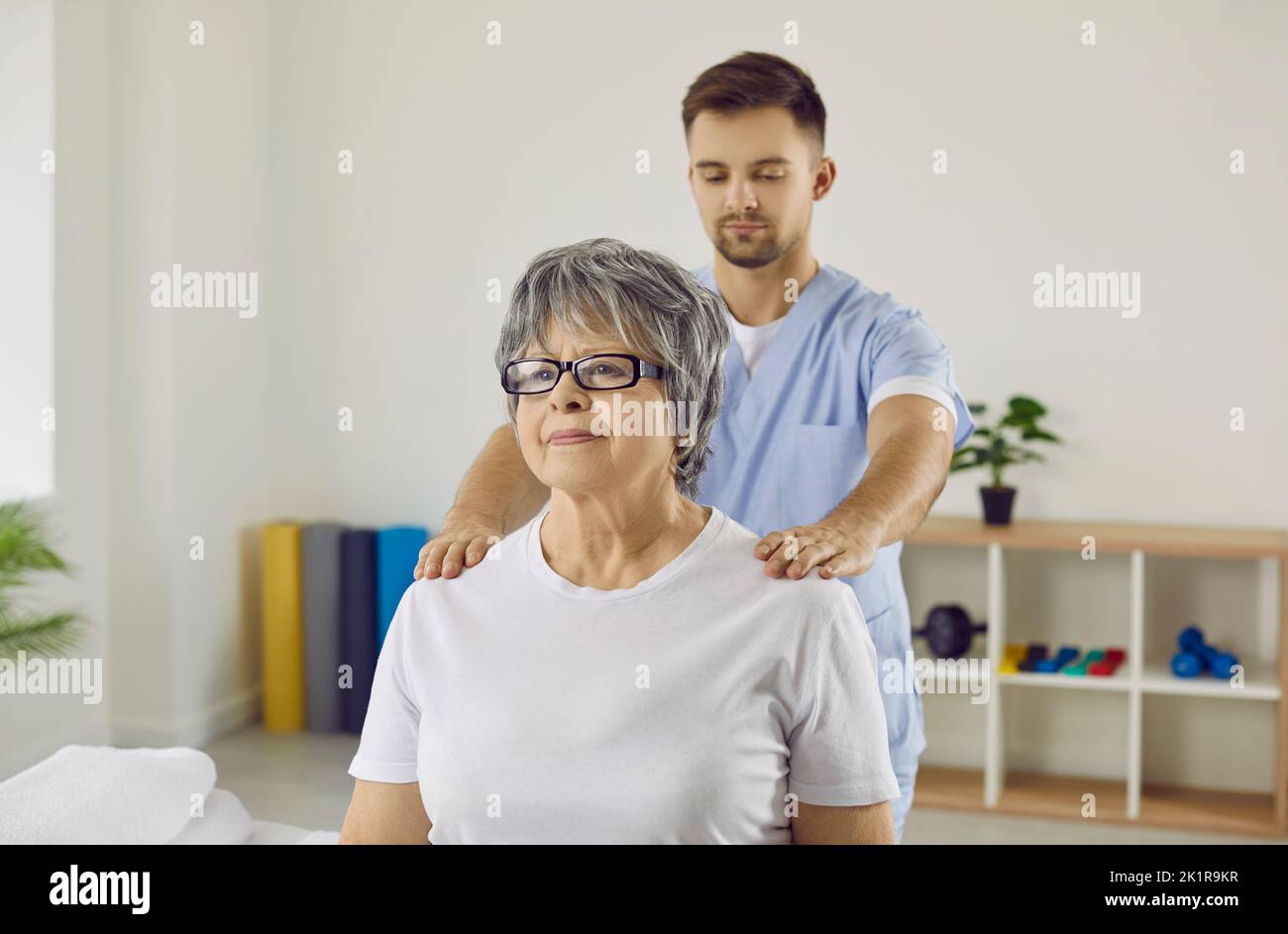 Fisioterapista maschile aiutare la donna anziana con il recupero del corpo Foto Stock