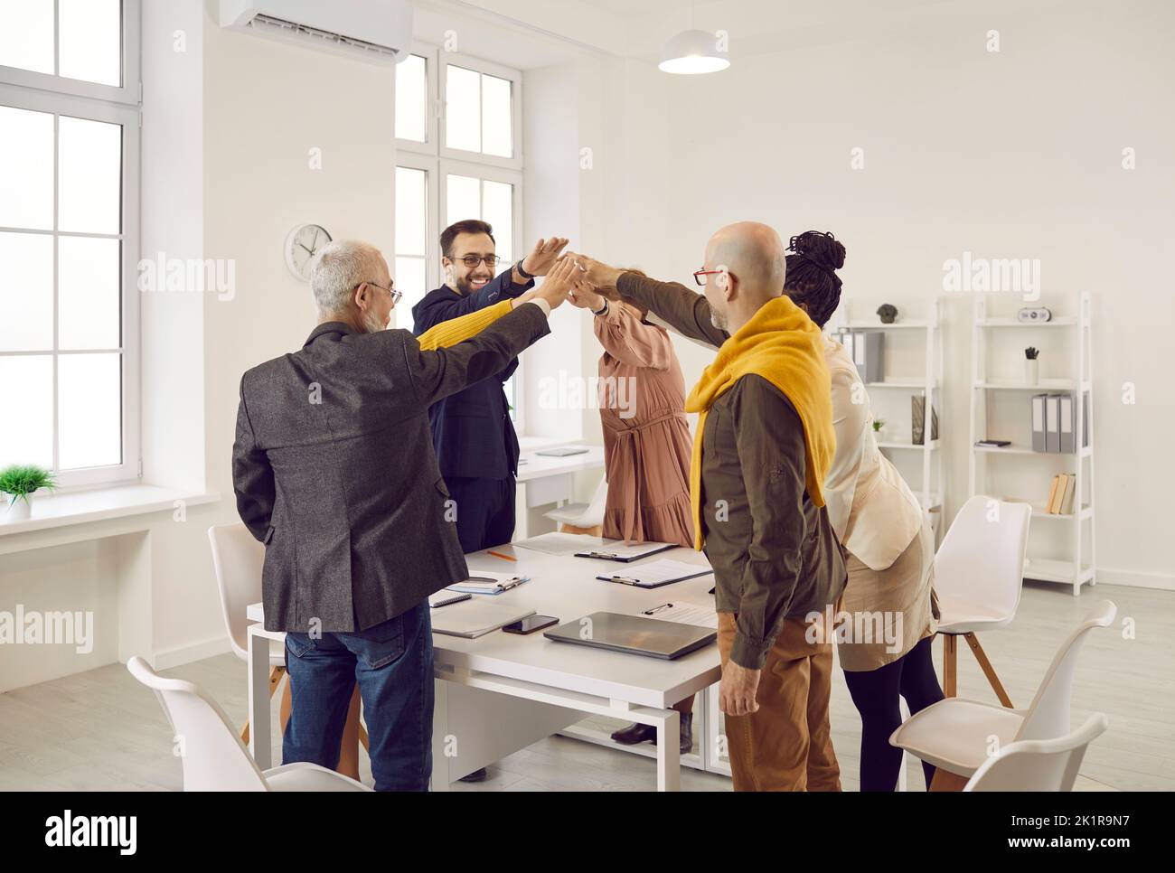Sorridendo uomini d'affari diversi danno alti cinque in ufficio Foto Stock