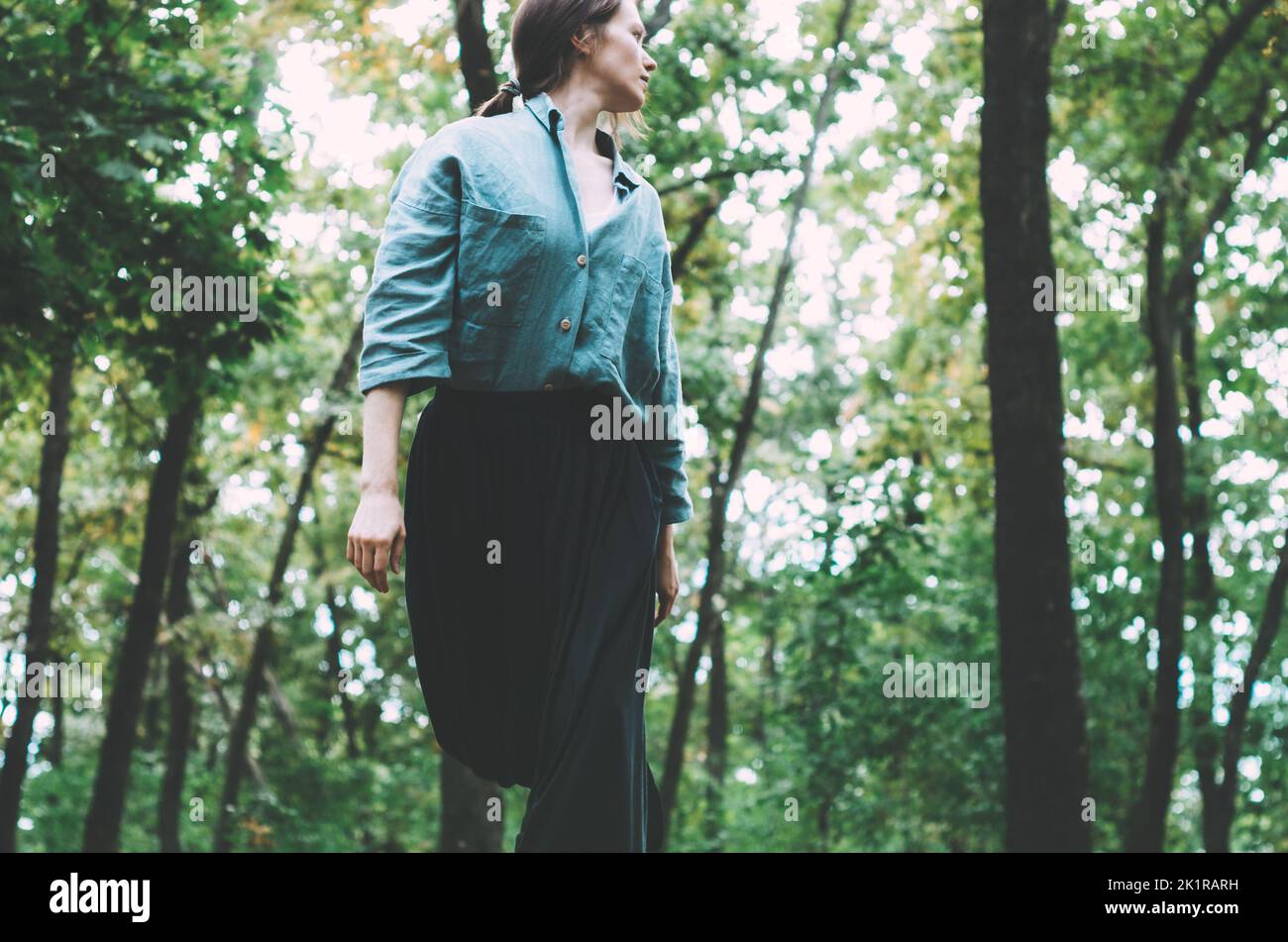 Donna che cammina nel bosco, guardando indietro Foto Stock