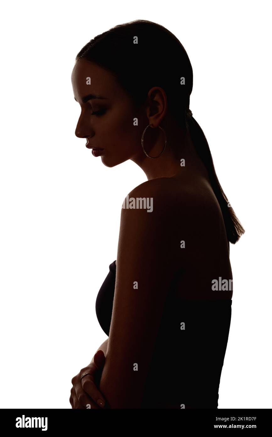 Donna silhouette. Abuso femminile. Discriminazione di genere. Contrasto scuro contorno ritratto profilo di depresso hurt imbarazzato vittima signora guardando giù io Foto Stock