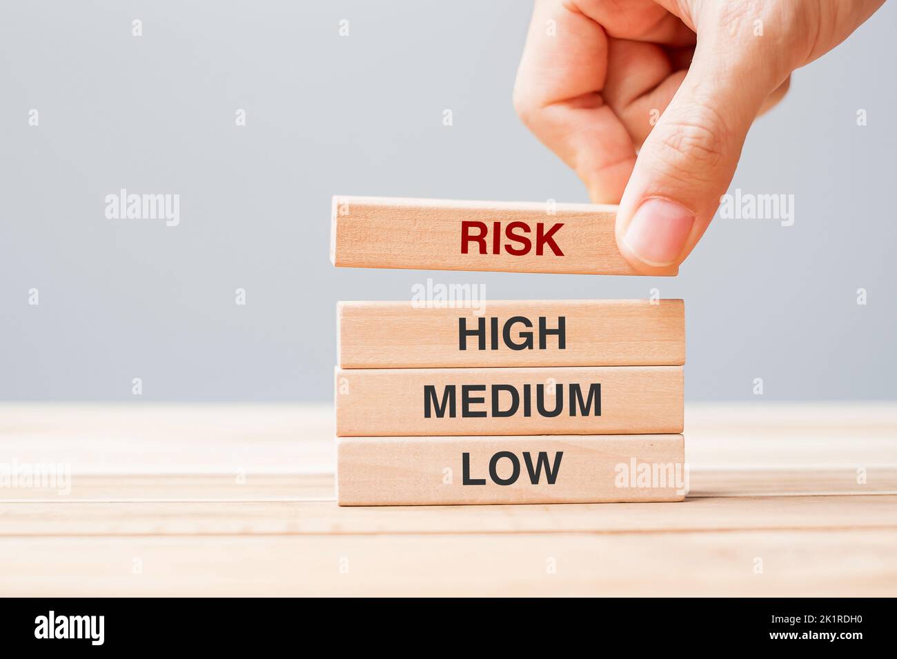 Mano di businessman che posiziona o tira il blocco di legno con il testo di rischio sopra alto medio e basso. Pianificazione, gestione di rischio, economico, finanziario e C corporativo Foto Stock