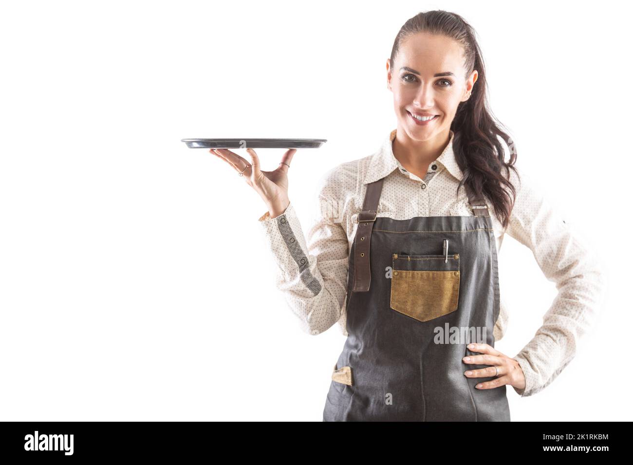 La cameriera che tiene in mano un vassoio è vestita di grembiule posato su un fondo isolato. Foto Stock