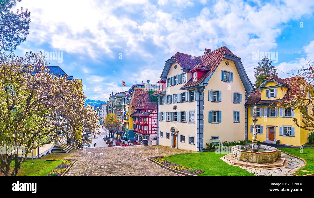 Splendide case medievali con una piccola fontana in pietra e un albero fiorito nel centro di Lucerna, in Svizzera Foto Stock