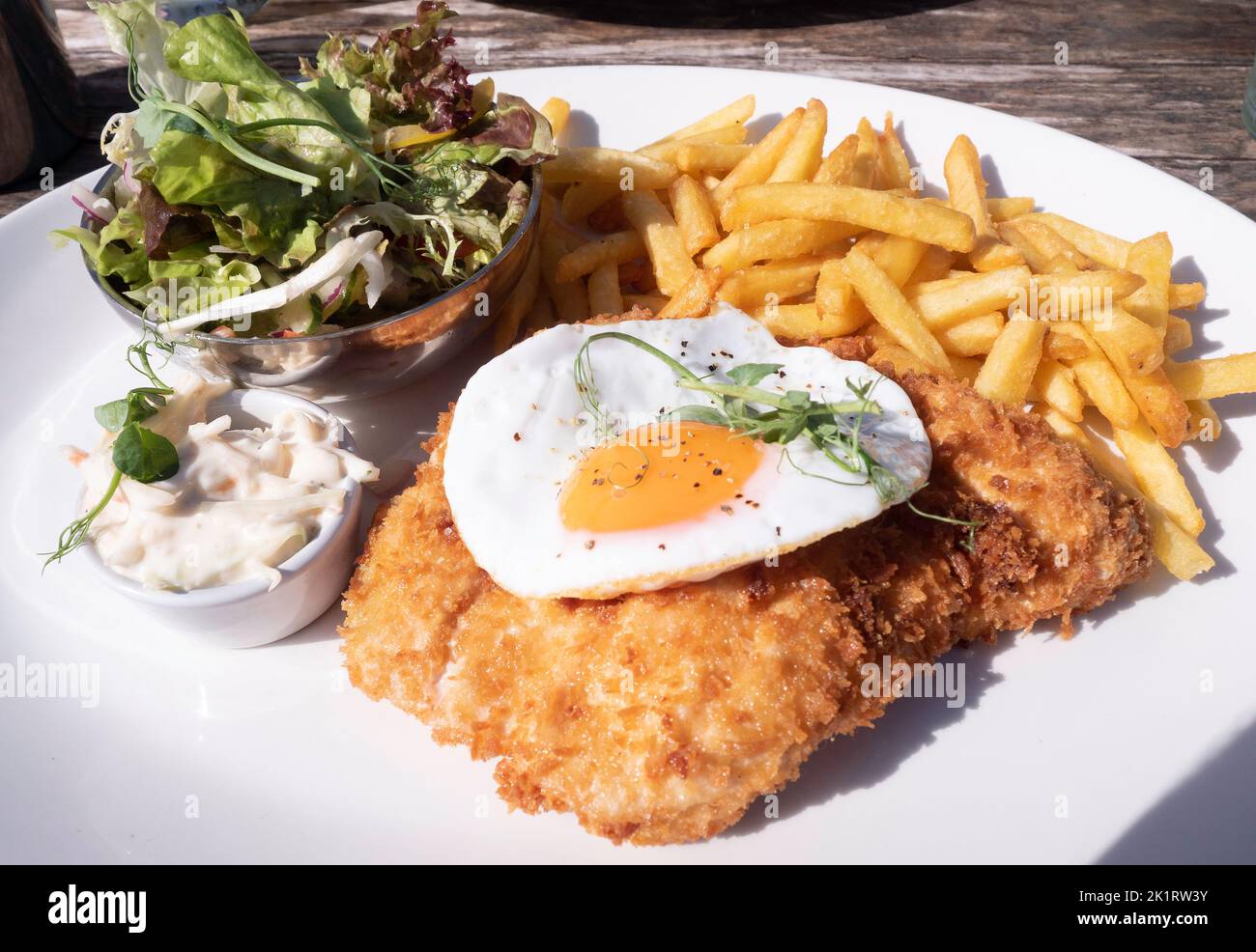 Lord Stones Café pranzo Pollo milanese con patatine coleslaw e miscela foglie insalata con un uovo fritto sulla parte superiore Foto Stock