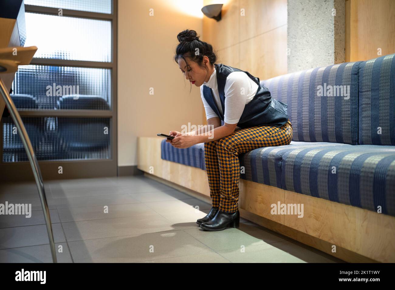 donna d'affari che usa lo smartphone nella hall dell'ufficio Foto Stock