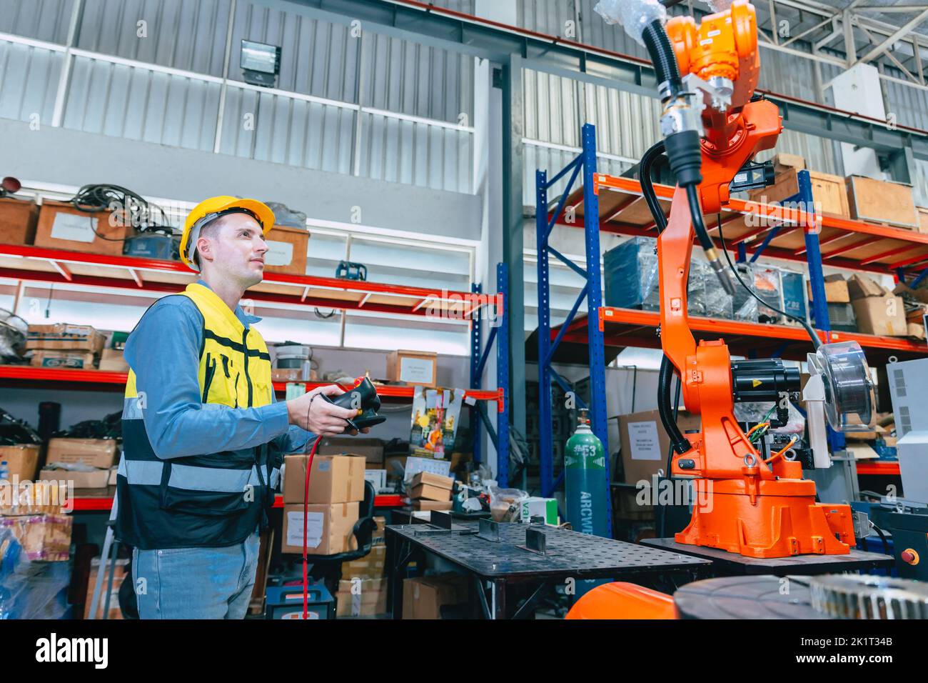 Ingegnere caucasico lavoratore maschio che lavora in fabbrica di metallo con robot saldatore programmatore controller e monitor. Foto Stock