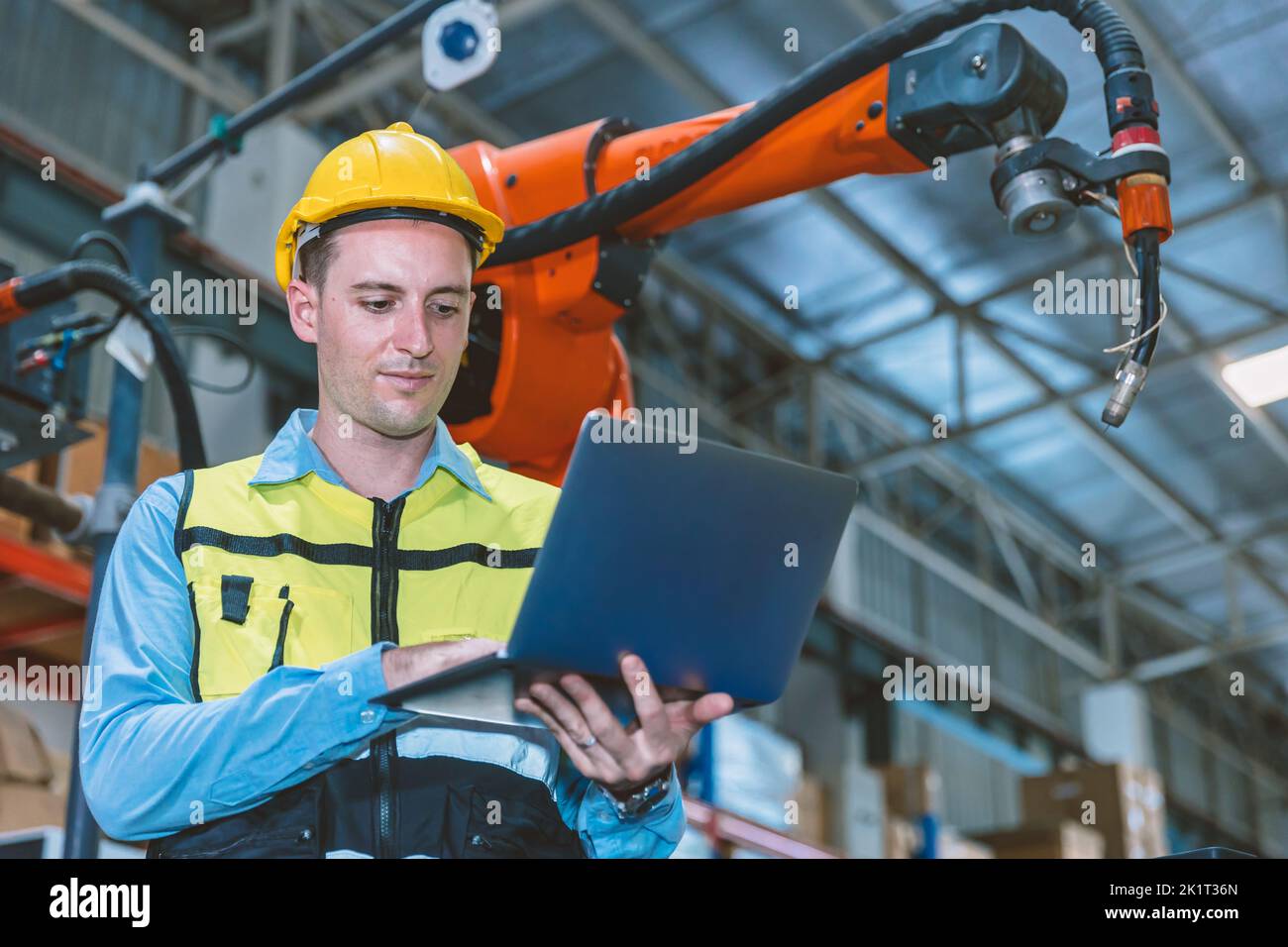Ingegnere caucasico lavoratore maschio che lavora in fabbrica di metallo con robot saldatore programmatore controller e monitor. Foto Stock