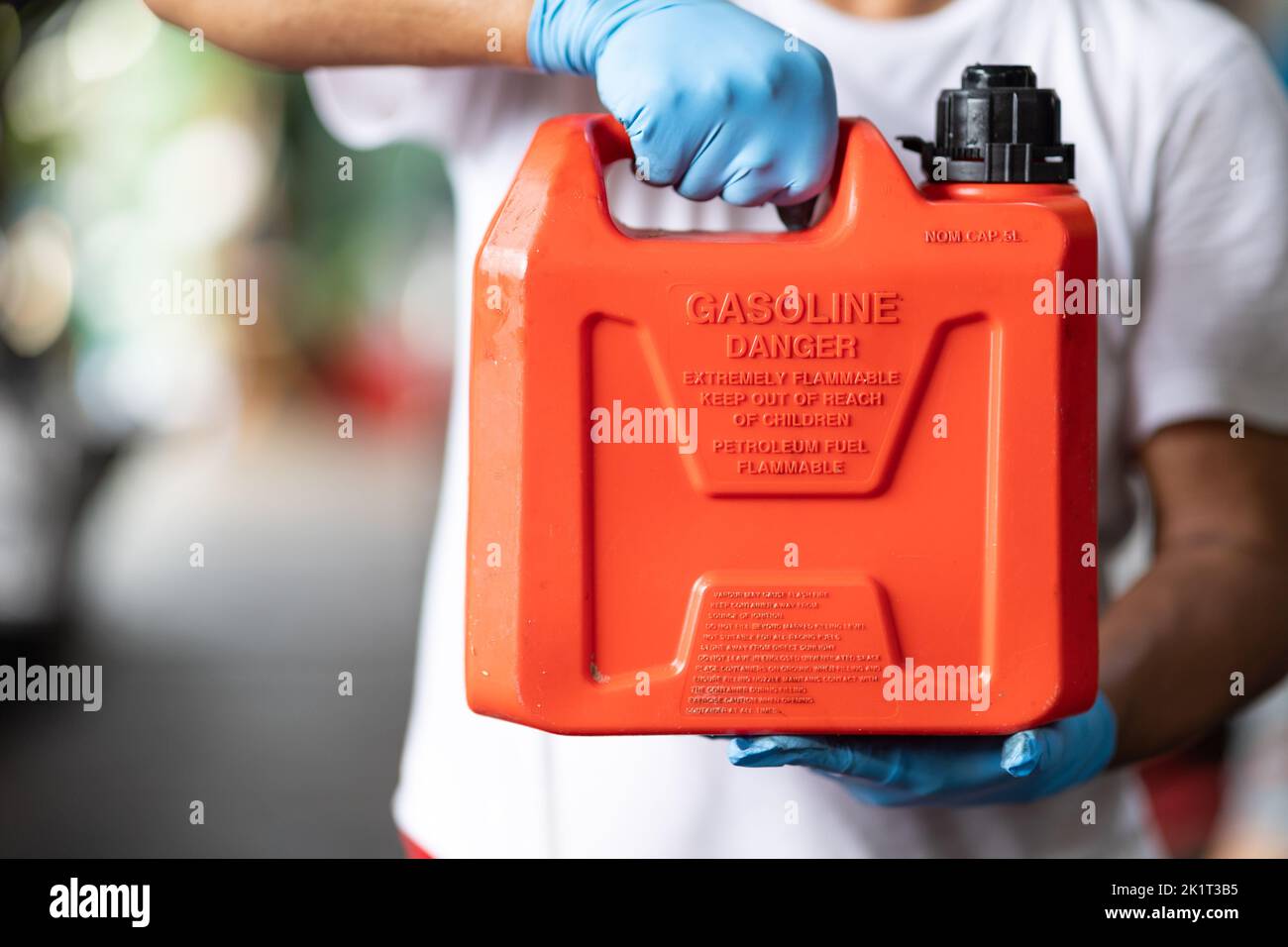 man manico rosso plastica carburante gallone materiale infiammabile contenitore per riempire serbatoio di benzina auto Foto Stock