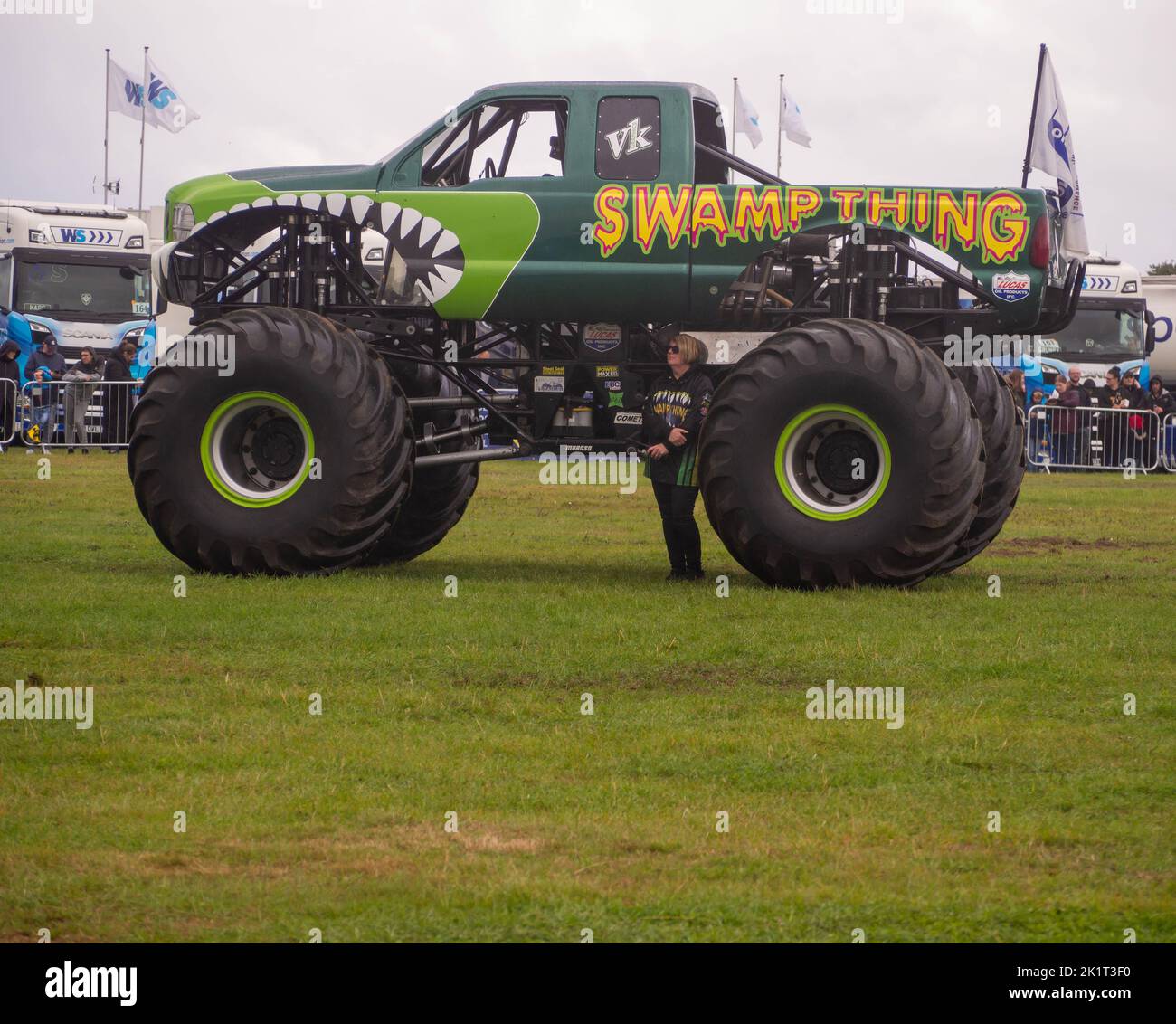 Swamp Thing Monster Truck dimostra quanto sia grande con il partner del proprietario sotto di esso. Foto Stock