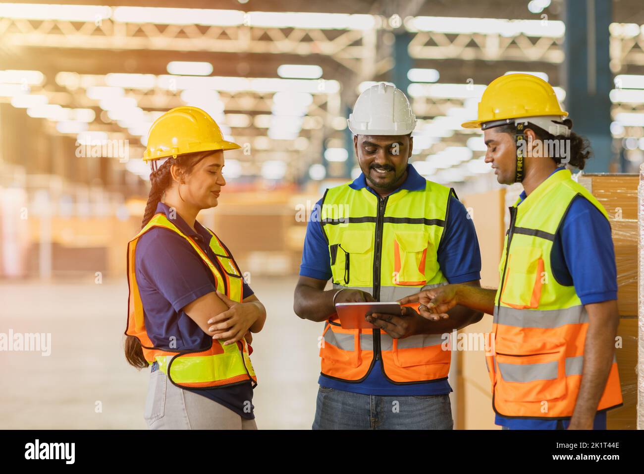 Lavoratore indiano lavoro di squadra maschio che lavora con le donne ingegnere parlare insieme in più grande fabbrica magazzino sorriso felice. Foto Stock