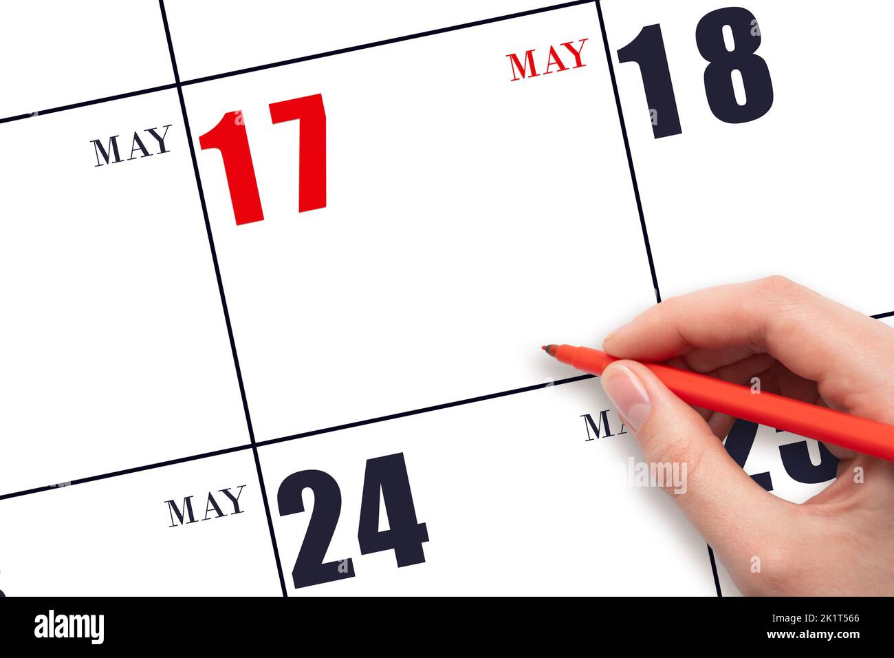 17th° giorno di maggio. Una mano che tiene una penna rossa e indica la data del calendario 17 maggio. Data calendario rossa, spazio copia, mockup. Mese di primavera, giorno del voi Foto Stock