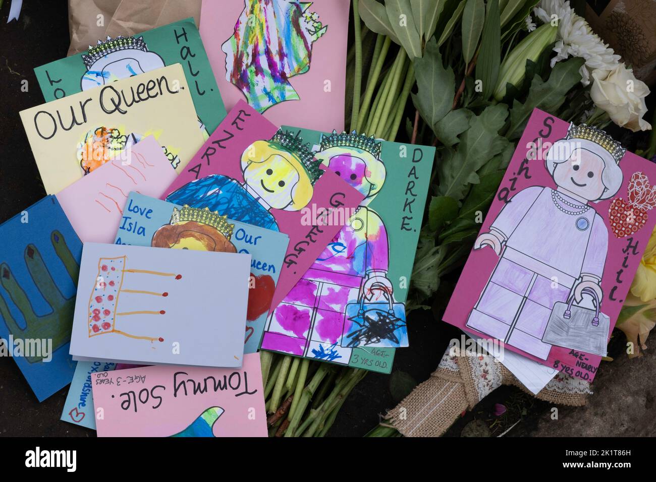 Carte e testi disegnati a mano per bambini collocati tra i fiori alle porte del Castello di Windsor in omaggio alla Regina Elisabetta II Foto Stock
