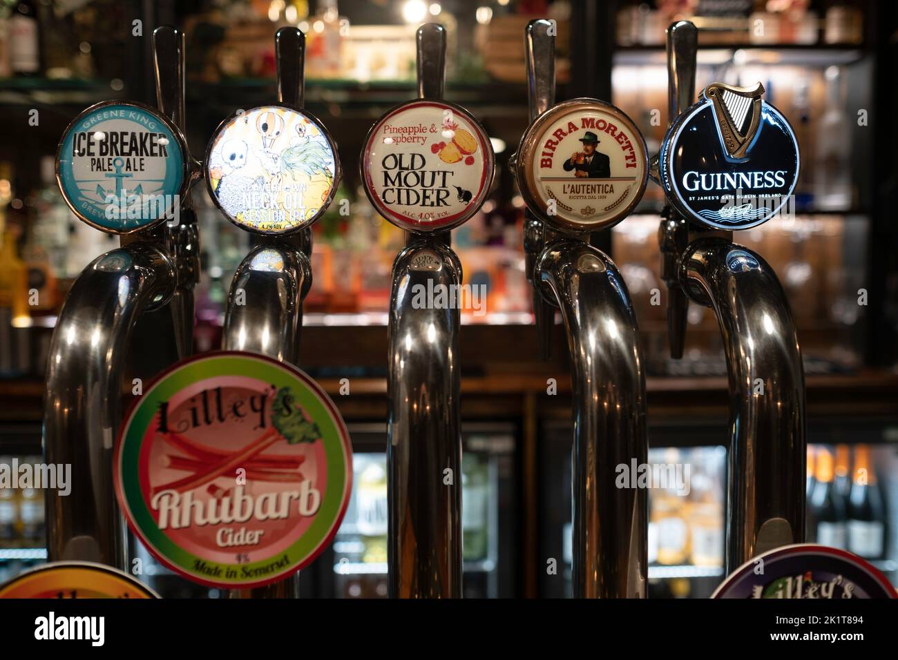 Birre alla spina in acciaio inossidabile in un pub inglese con diversi tipi e marche di birre e bevande. Profondità di campo ridotta Foto Stock