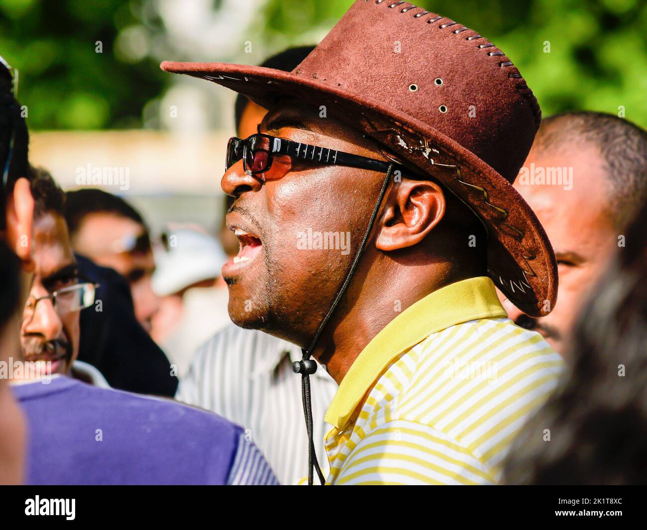 Londra Regno Unito Giugno 15 2009; uomo africano che indossa cappello e occhiali scuri con bocca aperta che chiama. Foto Stock