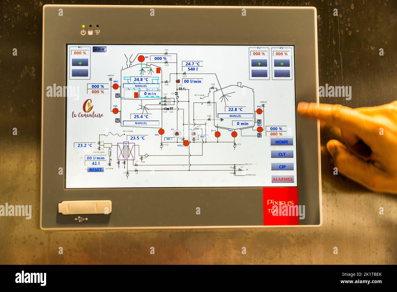 Il touchscreen di un'unità di controllo della marca Pixsys mostra il logo "La Canaulaise" insieme a un diagramma di flusso delle temperature e delle posizioni delle valvole del processo di brassaggio presso Les Brasseurs de l'Océan a Lacanau, Médoc, Francia. Una mano aziona il pannello di controllo. Foto Stock