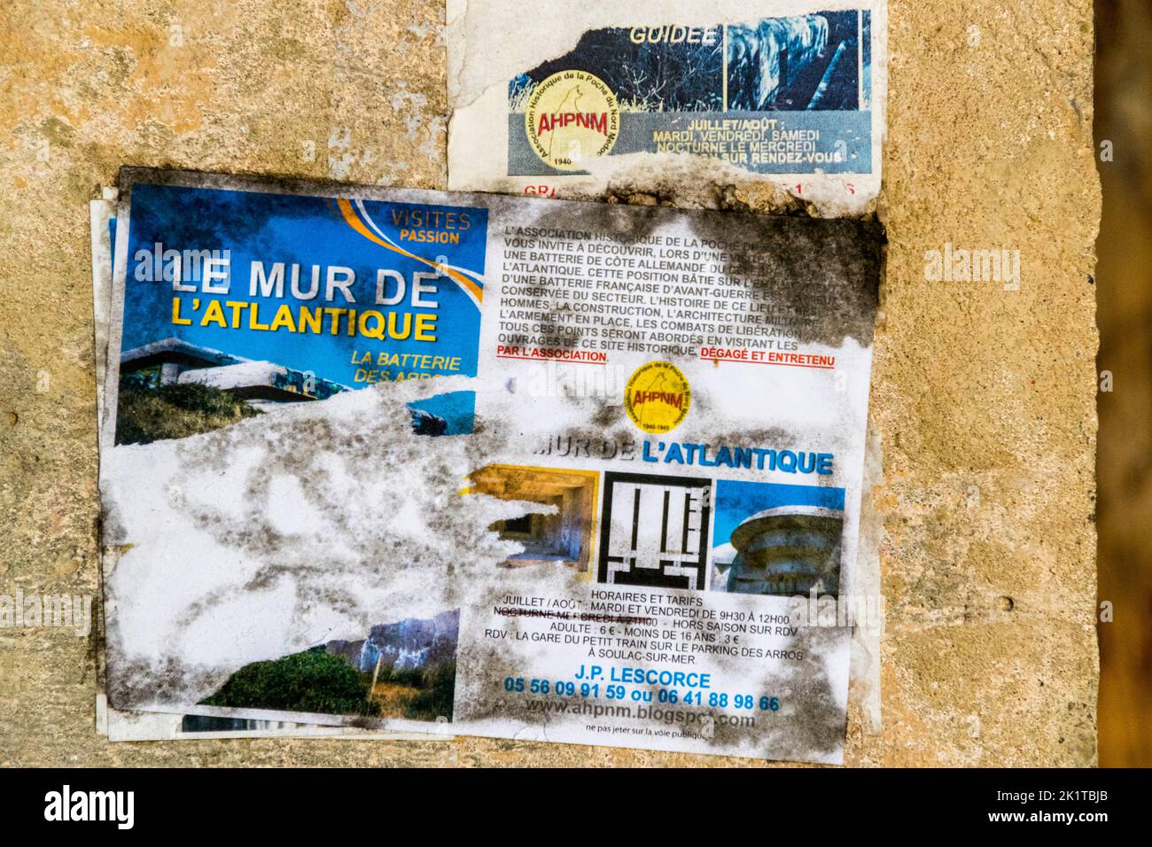 La Batteria dei Arros a nord di Soulac-sur-Mer nel Médoc, in Francia, presenta su una delle sue pareti del bunker un volantino dell'Association Historique de la Poche du Nord-Médoc (AHPNM) che promuove visite guidate sotto il titolo "Le Mur de l'Atlantique – La Batterie des Arros", con orari di apertura, prezzi di ammissione e un punto di incontro alla piccola stazione turistica nel parcheggio Les Arros a Soulac-sur-Mer. Un secondo volantino parzialmente scolorito sopra porta lo stesso logo dell'associazione. Il sito è tra gli ultimi sopravvissuti di circa 350 bunker che compongono la "Festung Gironde-Süd" (fortezza del Sud della Gironda) Foto Stock