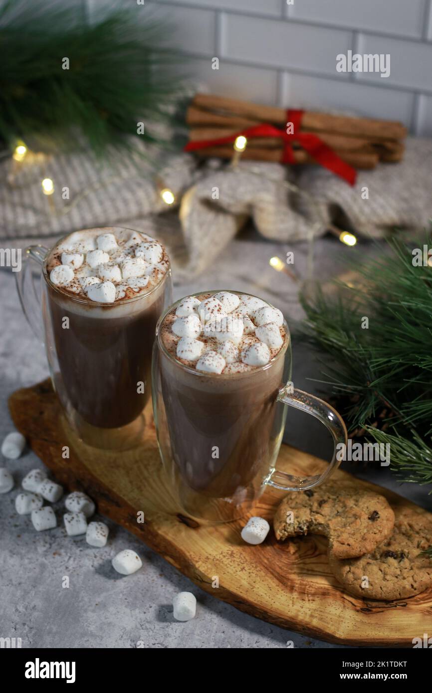 cioccolata calda in tazze di vetro con mini marshmallows sul tavolo grigio, sfondo di natale sfocato Foto Stock