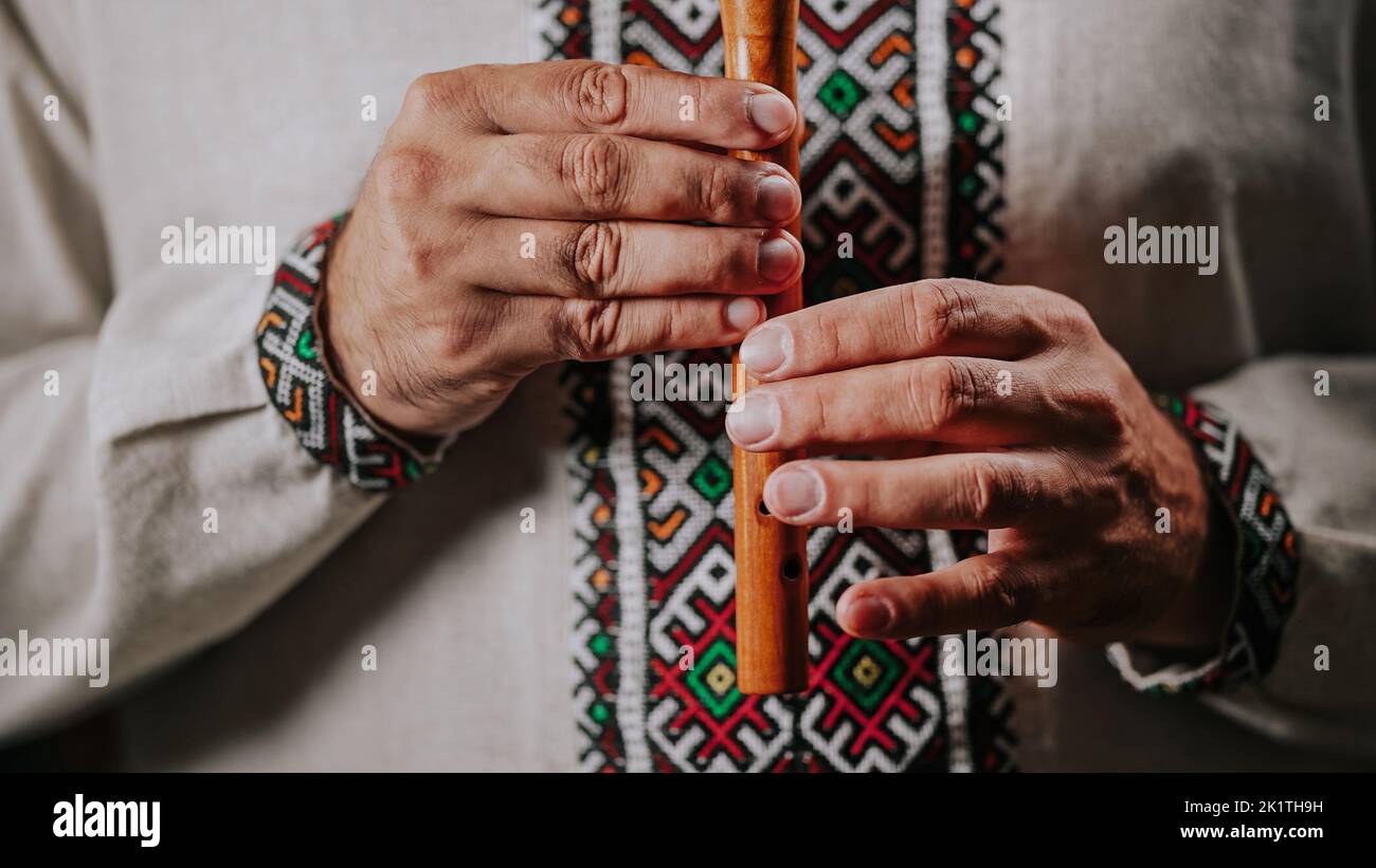 Mani di un uomo che gioca su flauto di legno di wind - sillitka ucraina su sfondo scuro. Concetto di musica folk. Strumento musicale. Musicista in tradizionale Foto Stock