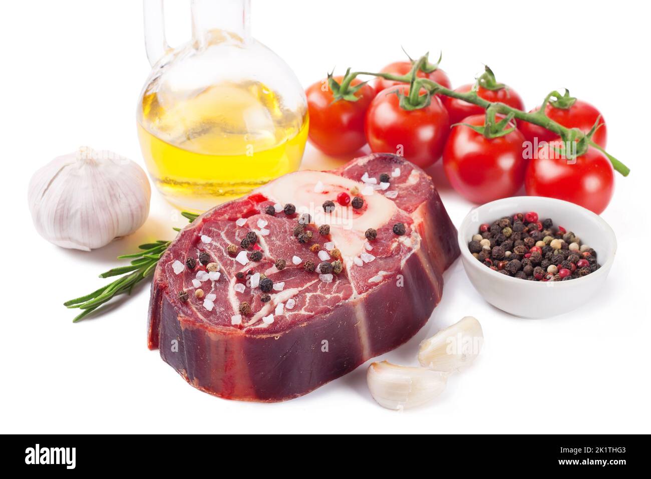 Bistecca di manzo crudo con osso, spezie, rosmarino e ingredienti da cucina isolati su sfondo bianco. Foto Stock