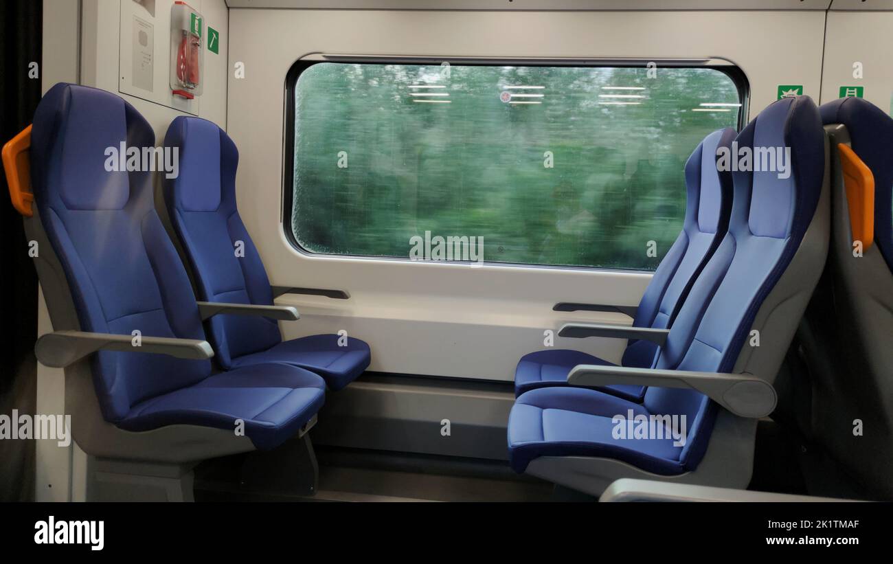 Finestra del treno con paesaggio sfocato e posti a sedere vuoti. Foto Stock