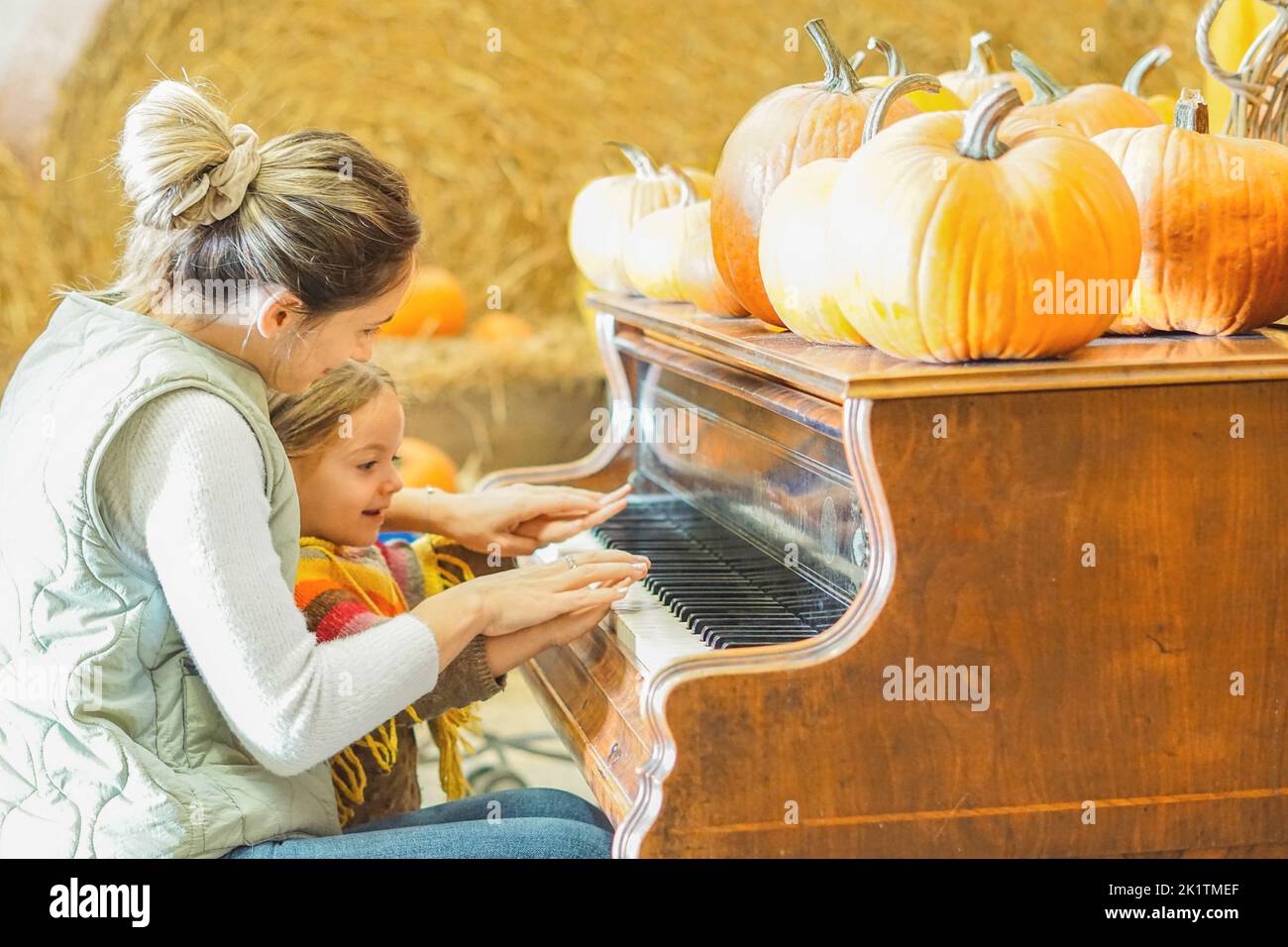 Madre che insegna a sua figlia come suonare il pianoforte nella stagione di Halloween - mamma e bambina che si godono la zucca patch Foto Stock