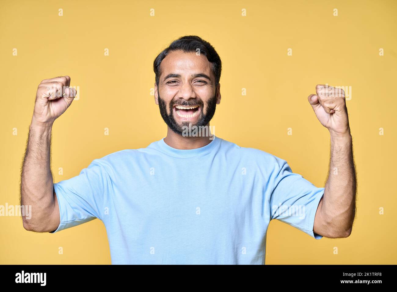 Felice eccitato indiano uomo alzando pugni isolati su sfondo giallo. Foto Stock