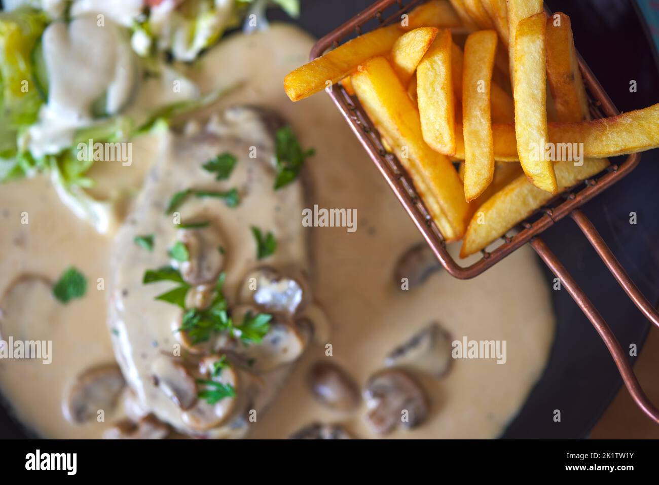 Patatine fritte e filetto di manzo con salsa di funghi sullo sfondo - vista ravvicinata Foto Stock
