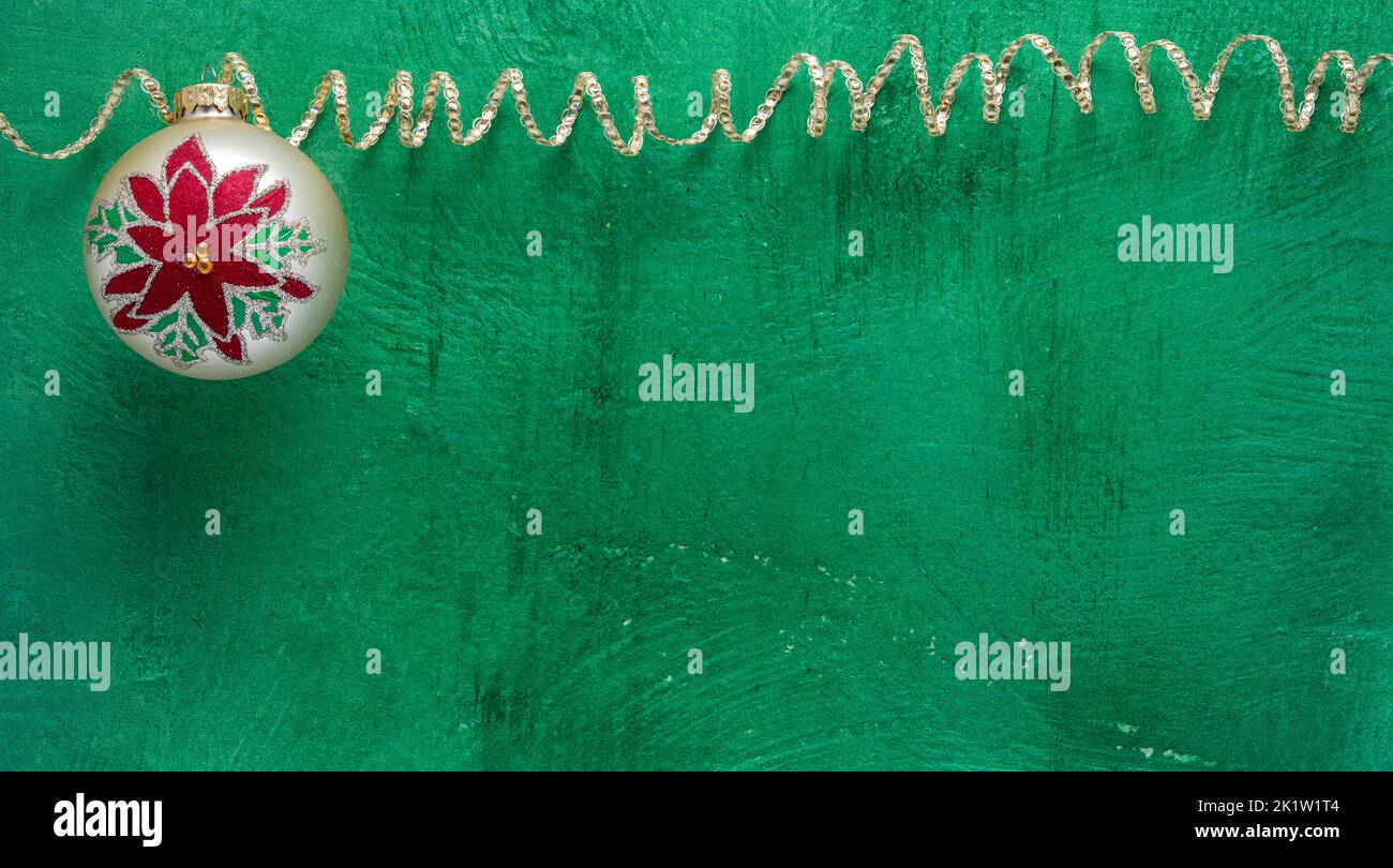 Tema natalizio o invernale con ornamento palla e nastro scintillante su sfondo verde brillante textured Foto Stock