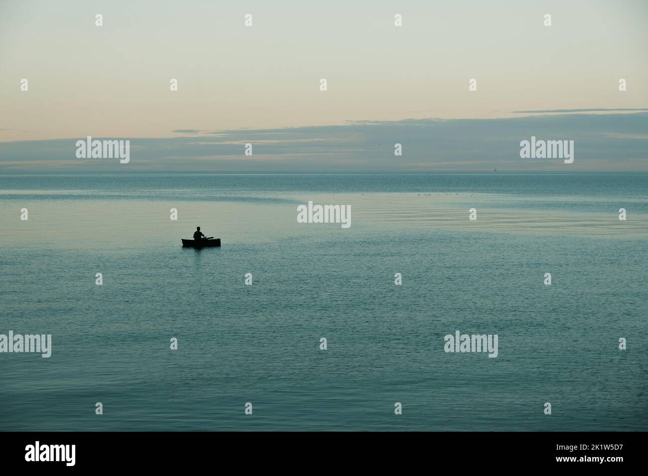 Una bella vista di un pescatore solitario in una barca Foto Stock