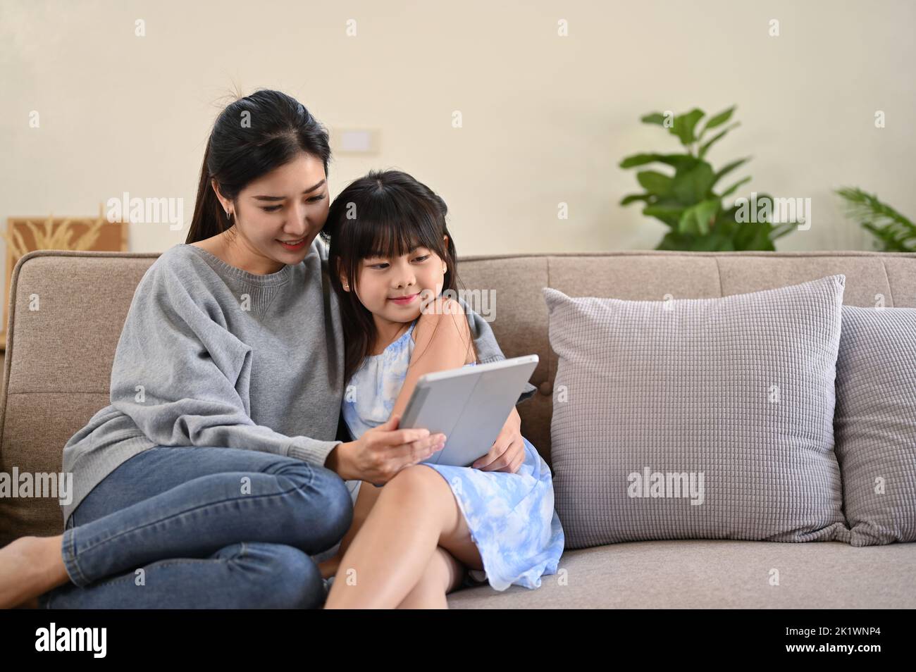Buon concetto di tempo della famiglia, Una mamma asiatica soddisfatta e gentile che usa il tablet, raccontando una storia, leggendo una storia di fiaba online a sua figlia carina mentre r Foto Stock