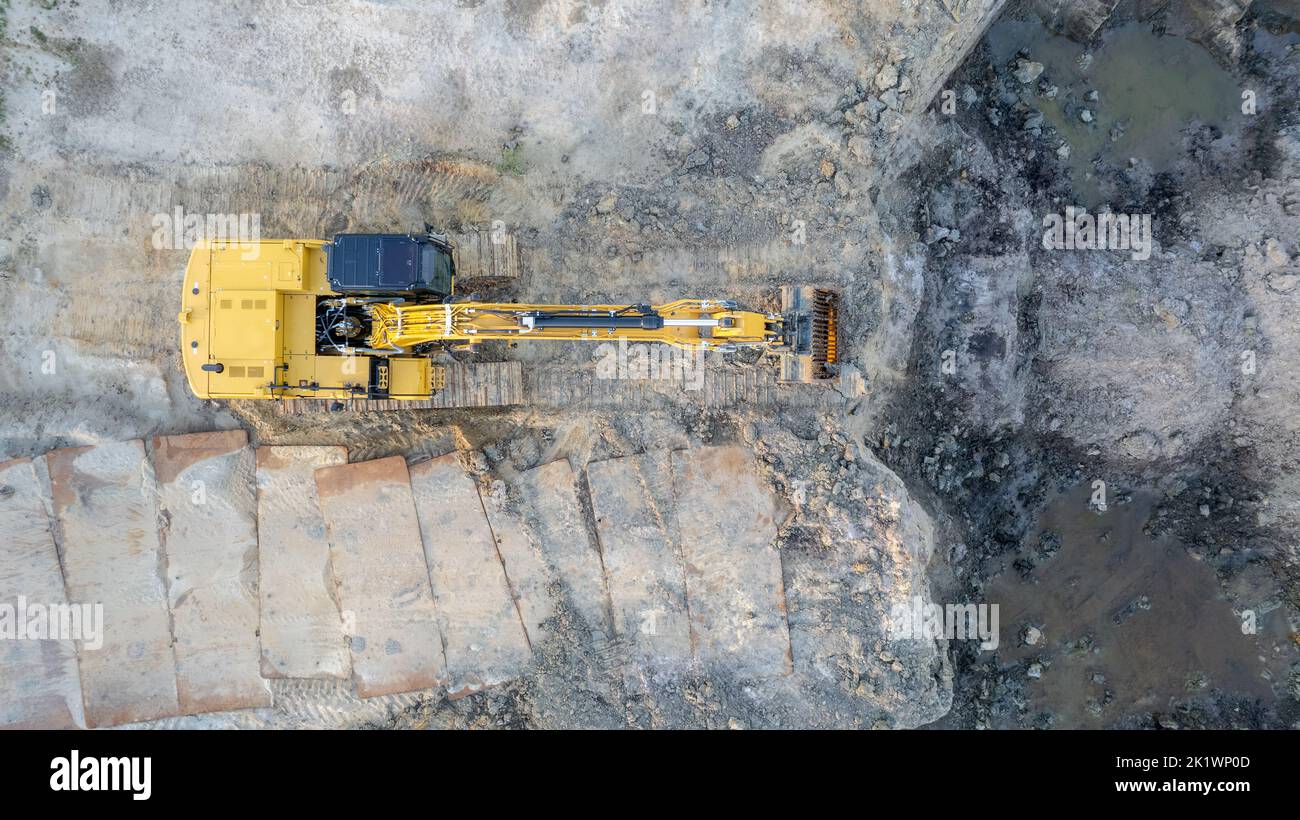 Bulldozer cingolato giallo esegue lavori di terra - ripresa aerea. Il trattore cingolato giallo rastrema il terreno per costruire una strada asfaltata. Il bulldozer di terra lavora durante la costruzione della strada di percorso. Foto di alta qualità Foto Stock