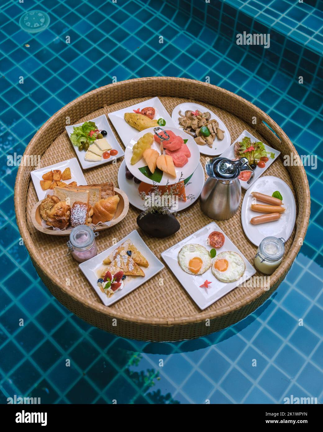 Vista dall'alto della colazione galleggiante in piscina, colazione galleggiante in piscina con uova di pane e frutta e caffè Foto Stock