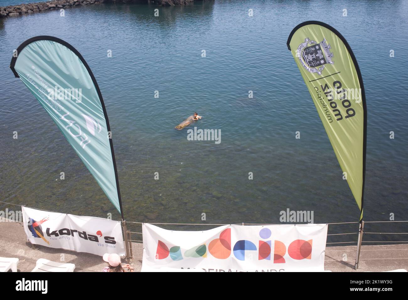 Piscina naturale di acqua oceanica a Seixal con ragazzo nuoto e striscioni al bordo Foto Stock