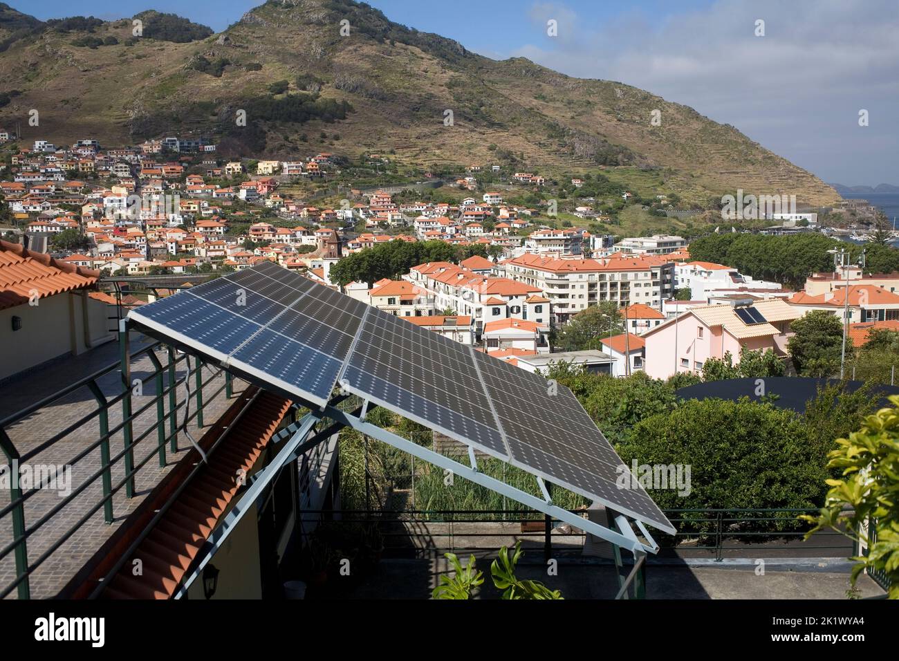 Pannelli solari su abitazioni domestiche a Machico, Madeira orientale, con la città oltre Foto Stock