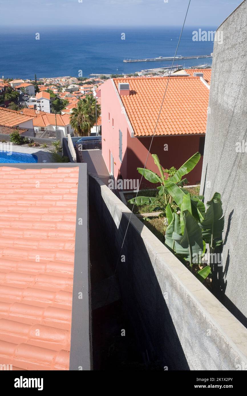 Vista verso il basso fino al porto sui tetti delle residenze in collina nella parte settentrionale di Funchal Madeira Foto Stock