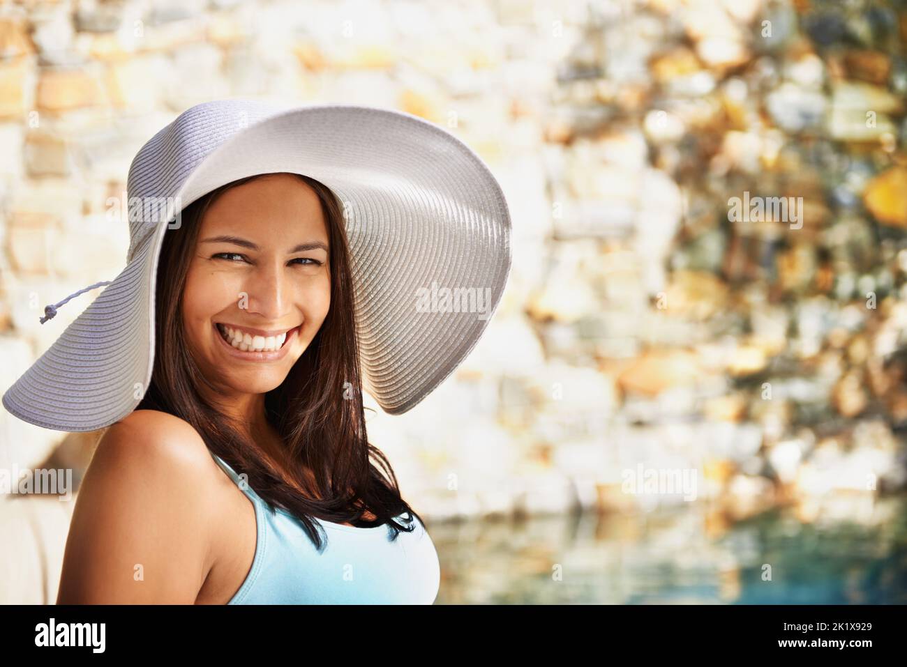 Stare al sicuro dal sole. Una donna attraente che indossa un cappello mentre si rilassa vicino a una piscina. Foto Stock