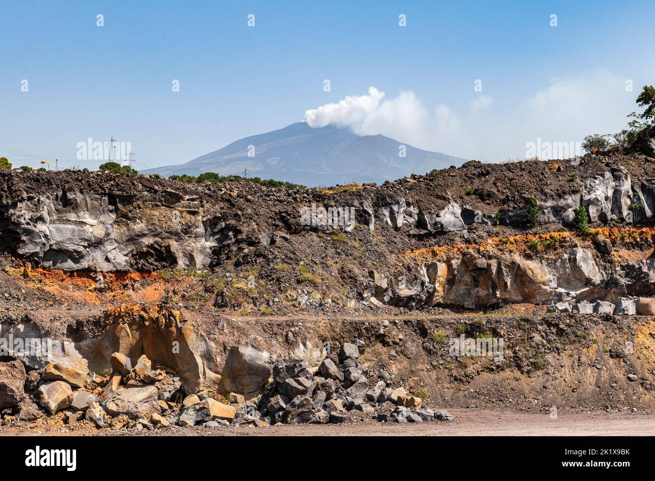 Vista dell'Etna da una cava di basalto sul fianco, con strati di depositi lavici provenienti da una serie di eruzioni dal 1669 (lo strato più basso) Foto Stock