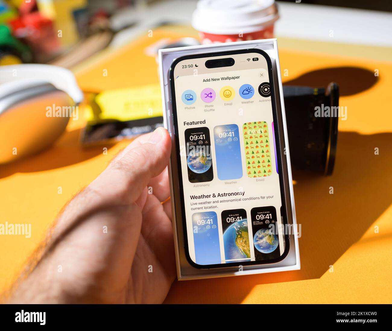 Parigi, Francia - 17 settembre 2022: Aggiungi una nuova sezione del menu di sfondo con caratteristiche e meteo astronomia categorie iOS 16 su iPhone 14 Pro di Apple computer unboxing in mano maschile Foto Stock