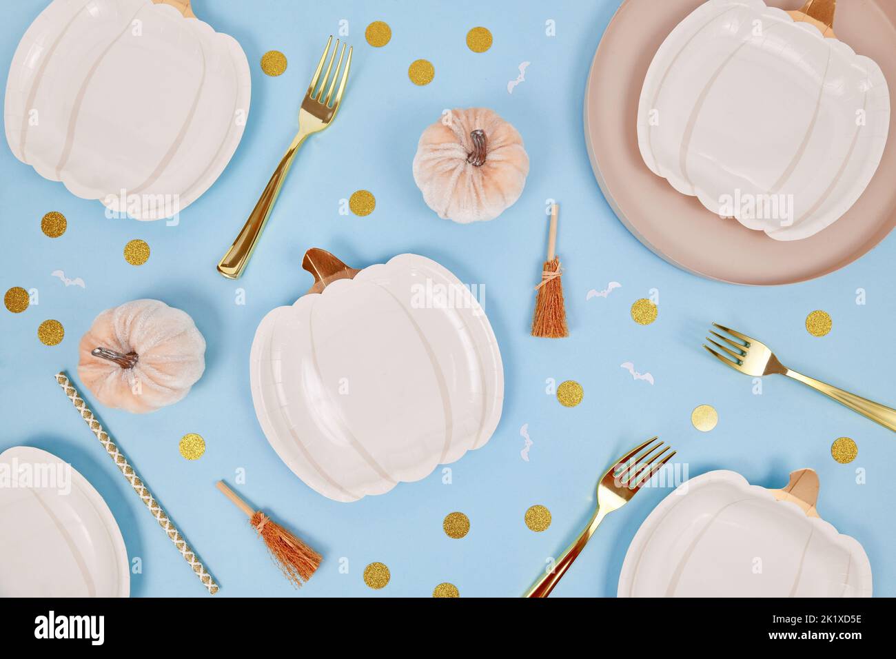 Piatto da festa di Halloween con piatti a forma di zucca color crema, scopa alle streghe e coriandoli dorati su sfondo blu Foto Stock