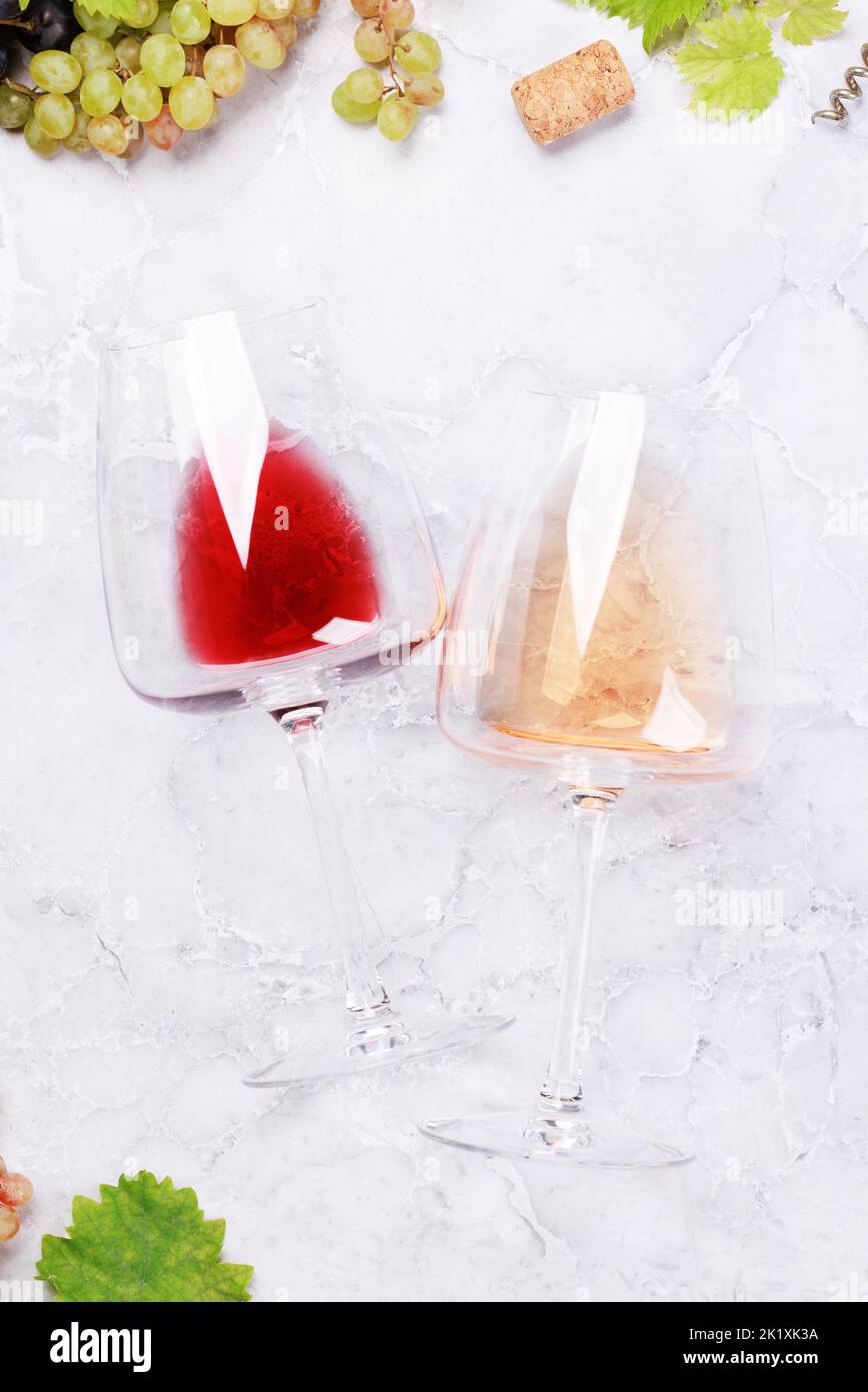 Bicchieri da vino rosso e rosa e uva. Giacitura piatta Foto Stock